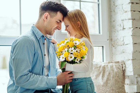 pai recebendo flores de Dia dos Pais amarelas e brancas da sua filha